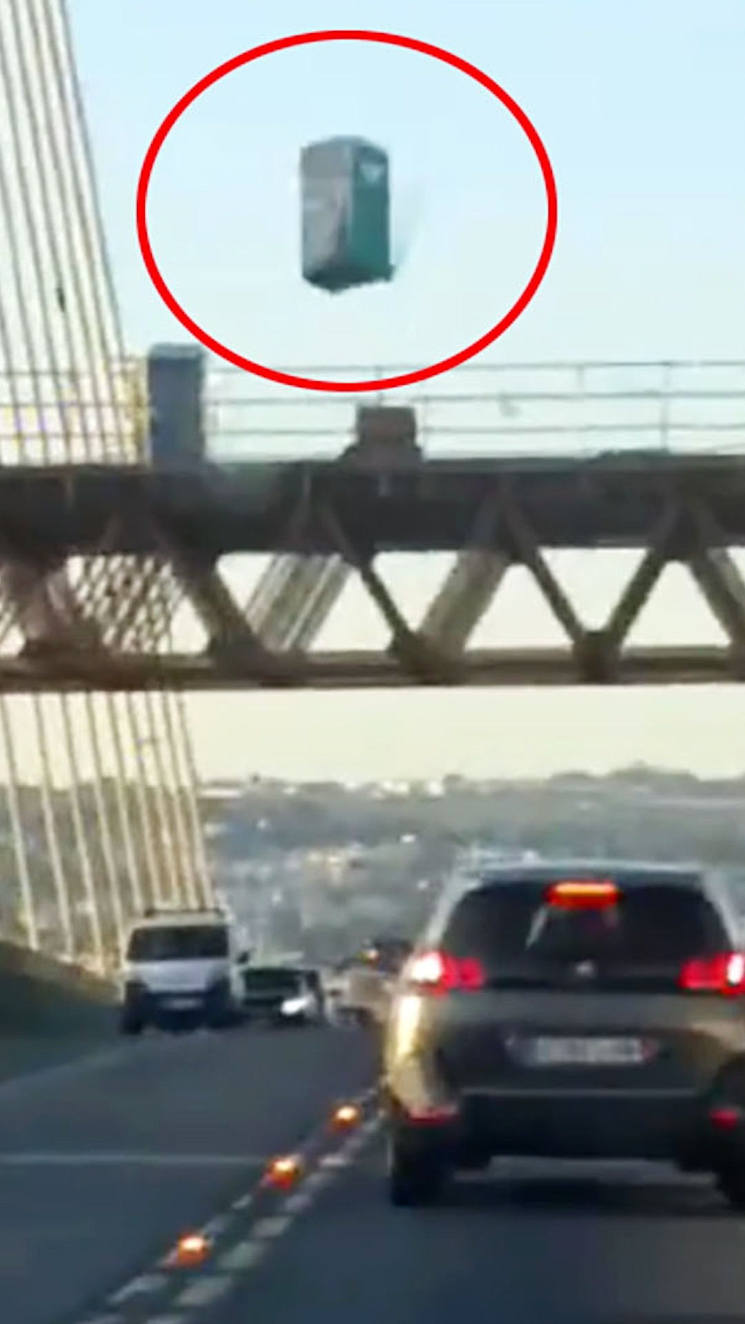 El momento de la caída de un aseo portátil de obra sobre el Puente del Centenario de Sevilla